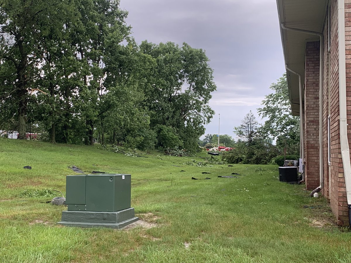 Storm damage in Beech Grove   that the sun is up. Lots of branches on the ground, trees snapped in half, one man already on the roof taking a look around at these apartments near the high school