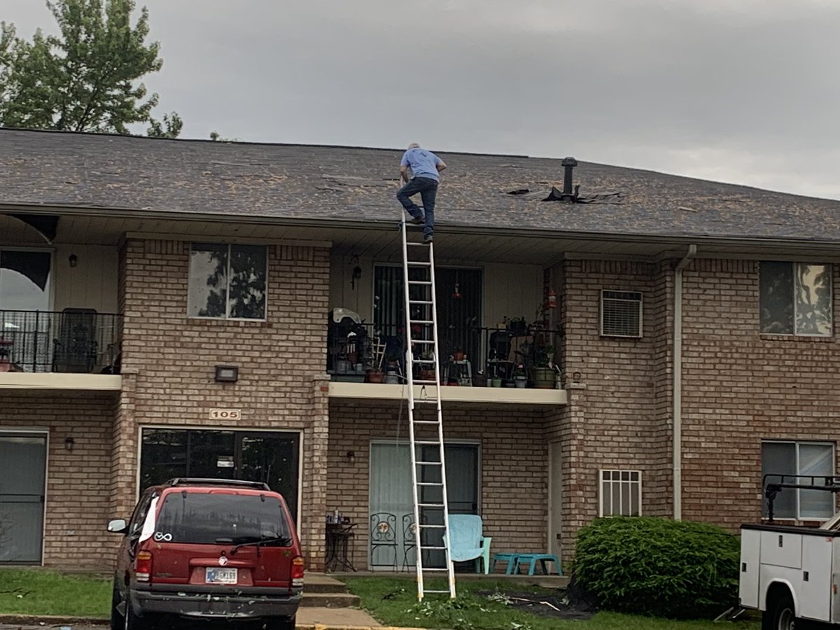 Storm damage in Beech Grove   that the sun is up. Lots of branches on the ground, trees snapped in half, one man already on the roof taking a look around at these apartments near the high school